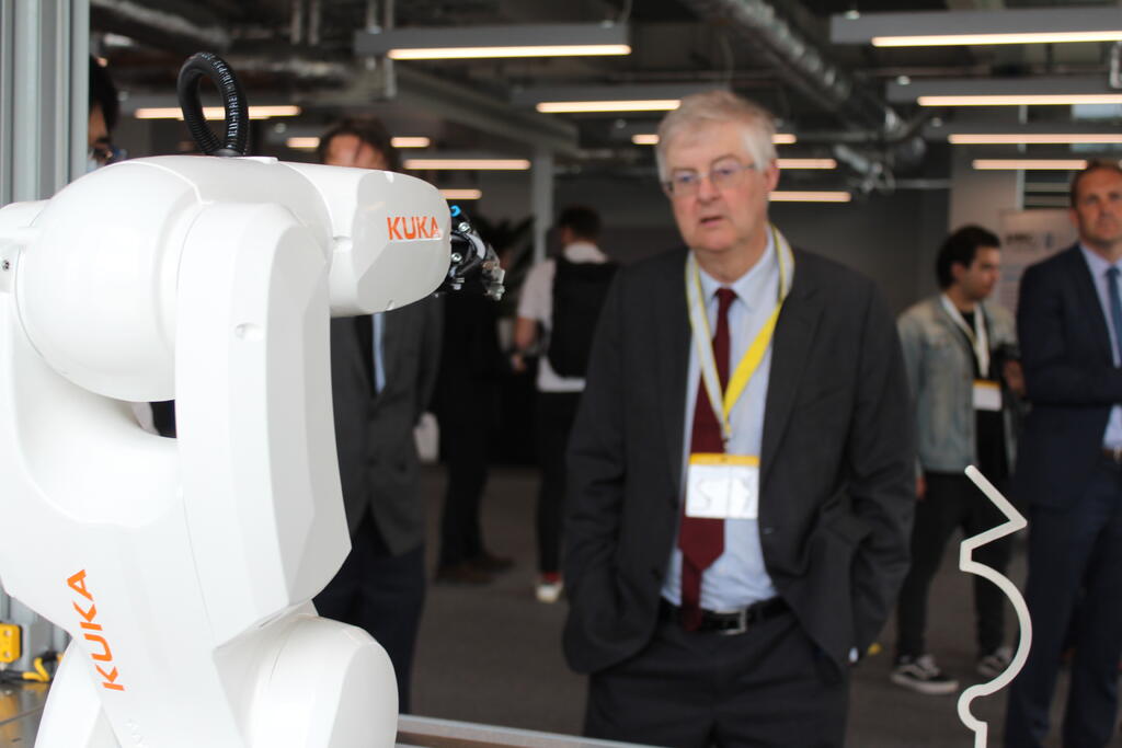 First Minister of Wales, Mark Drakeford, studies a KUKA robot.