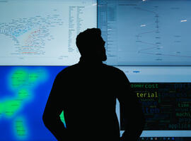 An AMRC engineer standing in front of screens showing AI machine learning