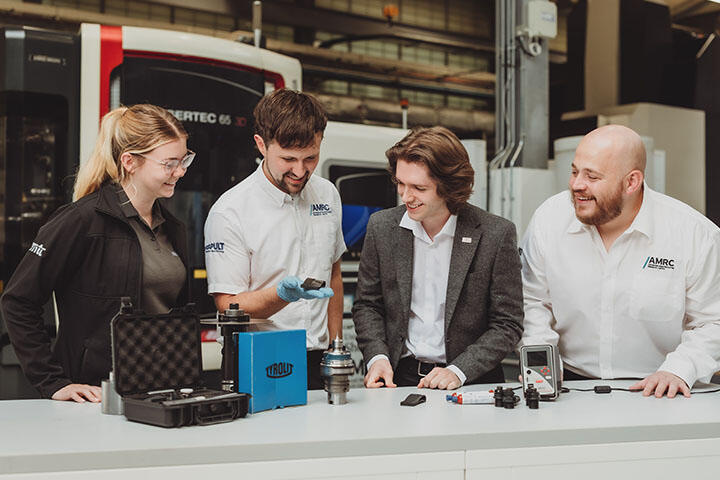 Four engineers look over component parts