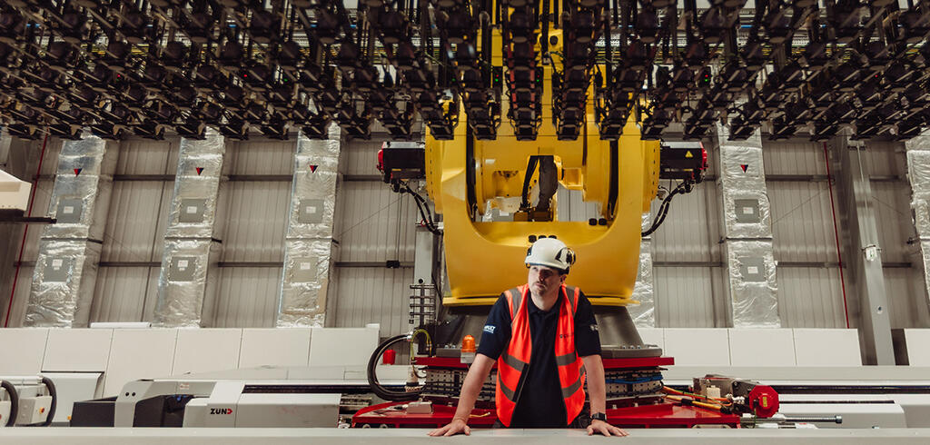 A man in a hard hat looks up at the COMPASS facility
